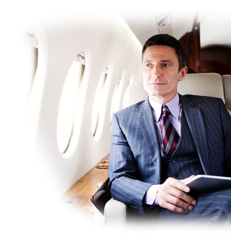 A Man in a Suit Looking Outside From a Jet Window